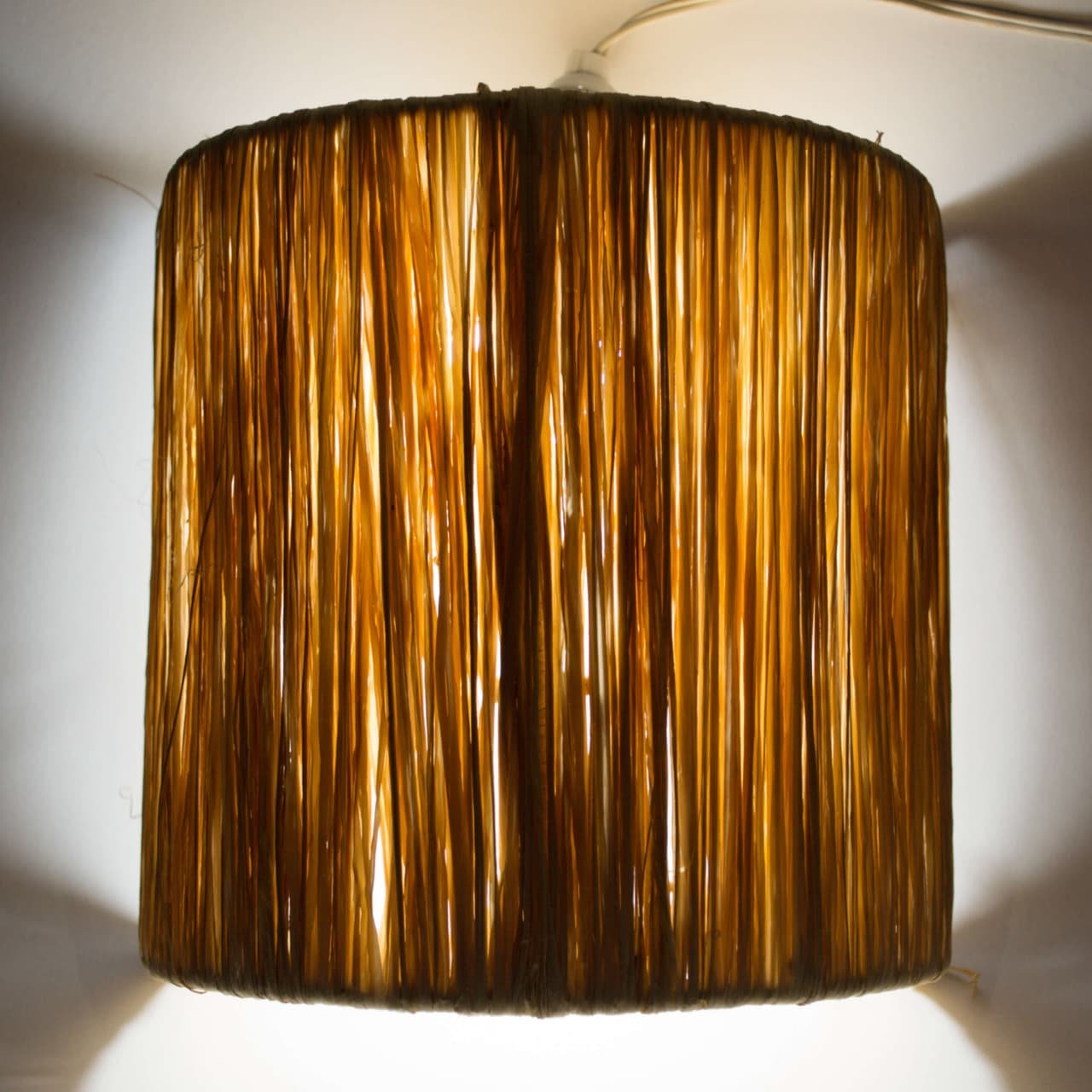 Cylindrical wrought iron frame pendant light wrapped in natural raffia fibers handcrafted in Marrakech